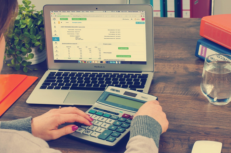 person checking financial paperwork and calculator at desk
